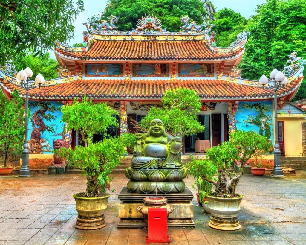 Laughing Buddha statue in front of a pagoda at the Marble Mountains in Da Nang