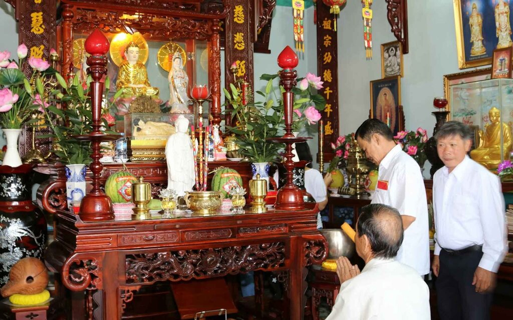 Worshippers pray before an altar with incense, offerings and Buddhist statues, a common scene of religion in Vietnam